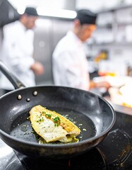 Kitchen scene in a restaurant showcasing the cooking of white fish fillet by chefs working in the background