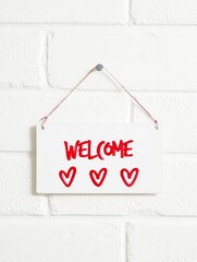 White square metal blank plate on white brick background with text Welcome.