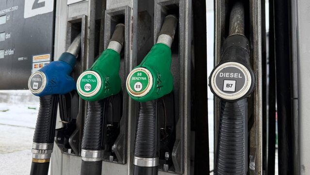 Multiple fuel pump nozzles at gas station showing diesel B7 and gasoline benzyna E5 E10 options in different colors at Polish petrol station