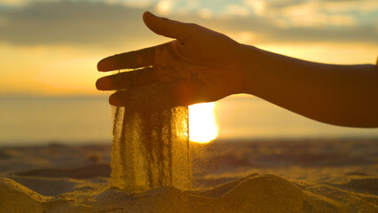 CLOSE UP: Sparkling grains of coarse sand fall out of unknown female's hand. © helivideo
