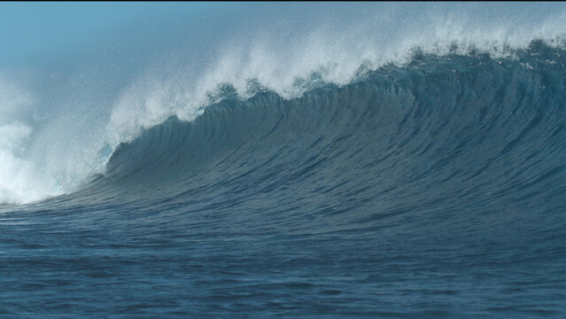 CLOSE UP: Cinematic deep blue ocean wave crashes and sprays the surroundings.