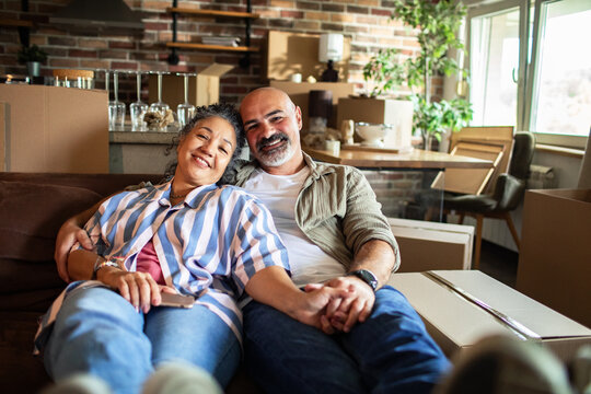 Happy mature couple relaxing on sofa in new home