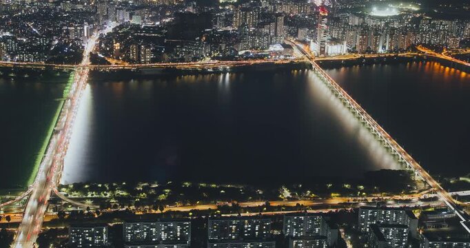 A nighttime view of a bustling city with illuminated bridges and flowing traffic over a river, highlighting urban vibrancy and movement. Time-lapse, Seoul, South Korea