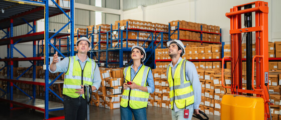 Warehouse worker in safety vest and hard hat in a large storage facility. Logistics, inventory...