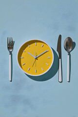 Clock with fork, knife, and spoon set on blue background at an unknown time