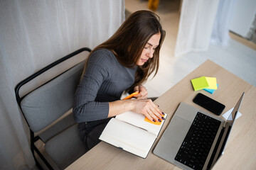 Young woman organizing notes working from home office