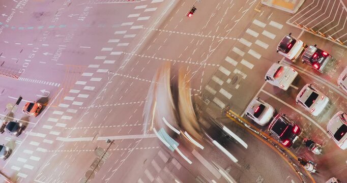 An urban intersection showcases dynamic traffic flow at night, with vehicles navigating crosswalks and traffic signals illuminating the scene. Time-lapse, Seoul, South Korea