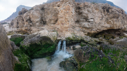 Obraz premium Waterfall Flowing Over Mossy Rocks