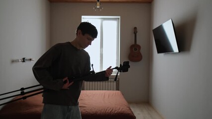 Content creation problems. Tired content creator records video in ordinary apartment, grabs tripod and plays air guitar. Real life lifestyle behind the scenes mood