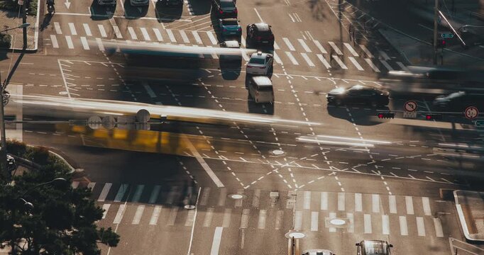 A bustling city intersection showcases vehicles in motion, creating a vibrant scene of urban traffic and movement across the crosswalks. Time-lapse, Seoul, South Korea