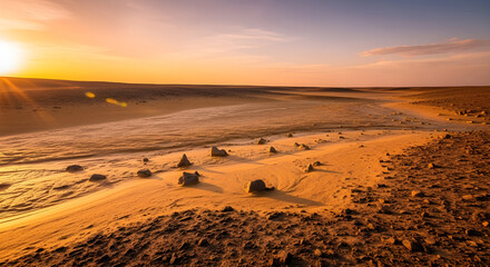 A serene desert landscape at sunset with a vast sandy expanse and rocky formations