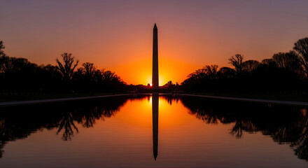 Washington Monument obelisk silhouette reflected in the Lincoln Memorial Reflecting Pool during a vibrant orange sunrise in Washington DC, iconic American landmark for patriotic concepts