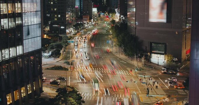 A bustling urban intersection at night captures the continuous flow of vehicles and bright city lights enhancing the lively atmosphere. Time-lapse, Seoul, South Korea