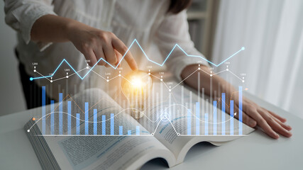 A woman engages in financial data analysis with charts and graphs open in a book, using a handheld device for insights into market trends and strategies. Scalp © InfiniteFlow