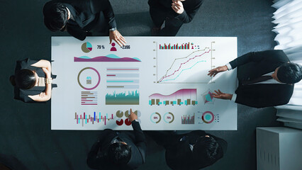 A collaborative business meeting showcasing professionals discussing data analysis with visual reports and graphs in a modern office environment. Axiom