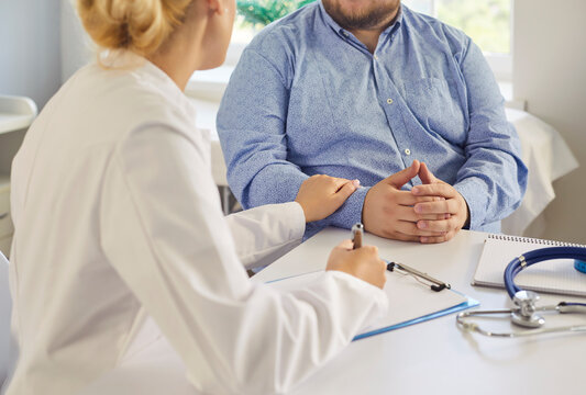 Doctor and patient consultation about obesity. Physician explains diagnosis and sets lifestyle goals with treatment options to fat overweight man in medical clinic. Support and medicine. 
