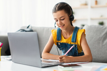 Homeschool little young girl student in headset learning during virtual internet online class with school teacher having remote meeting due to covid pandemic. Pupil studying foreign language or math