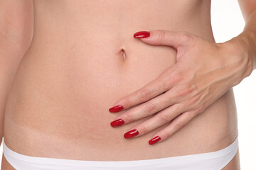 Close-up of a woman touching her belly skin around the navel for body care and skincare, studio...