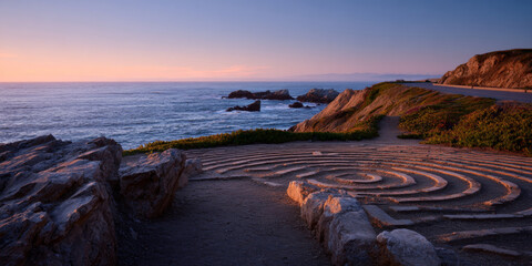 Coastal labyrinth carved into rocky terrain overlooking ocean at sunset with winding path and distant cliffs