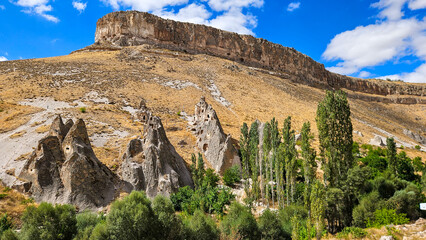 Ancient rock cut dwellings carved into a rugged mountain landscape representing historical settlement archaeology cultural heritage adventure tourism