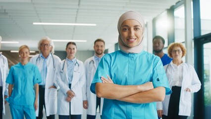Confident female medical worker standing in corridor. Smiling nurse showing professionalism while leading group of doctors behind her. Preparing for demanding tasks during busy hospital routine.