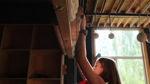 Sporty woman performs pull up exercise hanging on campus board. Strong blonde lady engages in workout demonstrating strength slow motion