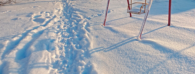 Snow-covered swing and path in snow, nostalgic mood, evoking winter memories and quiet solitude against serene snowy landscape