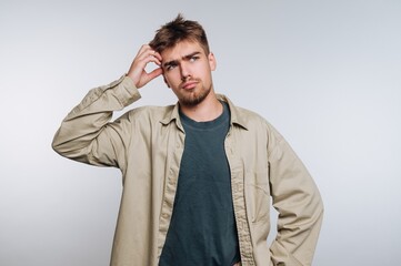 Young man with a puzzled expression scratching his head.