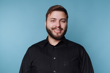 Obraz premium Smiling man in black shirt against blue background