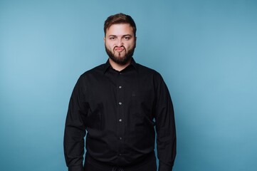 Obraz premium Man in black shirt making a funny face against blue background.