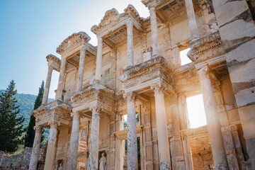 Obraz premium Library of celsus ancient roman architecture with intricate marble facade and columns standing against a bright blue sky, sunlight highlighting historical ruins in ephesus