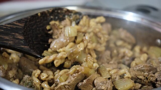 Creamy rotini Fusilli Macaroni and chicken liver with fried celery, vegetables. Preparation in stewpan, with savory sauce. Commercial kitchen