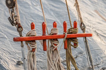 Nautical belaying pins with coiled ropes on traditional sailing vessel. © Trygve