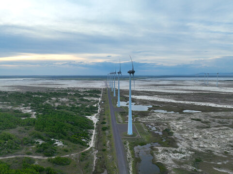 Aerial perspective of a long line of wind turbines extending into the