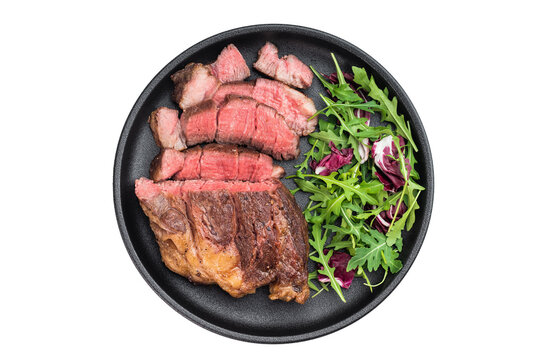 Sliced beef chuck eye roll steak cooked medium rare with fresh salad. Juicy beef meat served on isolated background.