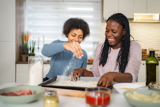 Black mother and daughter preparing homemade pizza together