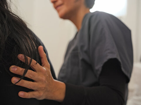 Native American nurse places her hand on patient's back while chatting