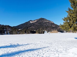 Snowy landscape of Bavarian Alps. Frozen lake of Spitzingsee offering a view of the elegant pyramid of the Brecherspitz, a triangular peak of immaculate white