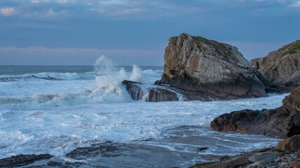 Waves erode the base of a rocky outcrop slowly
