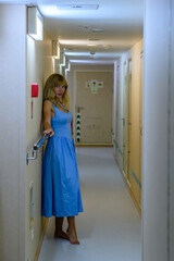 Elegant woman in a blue dress in a modern Russian hallway at night