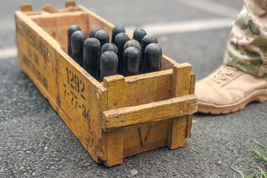 Military crate with black practice hand grenade case on asphalt