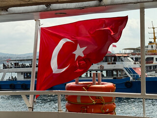Turkish flag waving on ferry above Bosphorus. National identity, travel, and maritime transport in Istanbul.