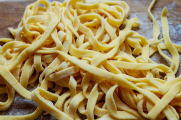 Freshly made raw egg pasta noodles arranged in nests on floured wooden board. Homemade italian food.