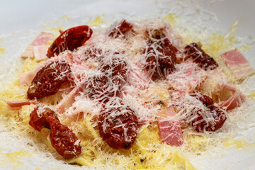 Homemade pasta carbonara with bacon, sun dried tomatoes and parmesan cheese. Creamy italian noodle dish.