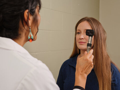 Native American nurse practitioner examines female patient's eyes