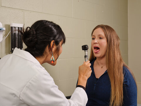 Native American nurse practitioner examines woman's mouth in clinic