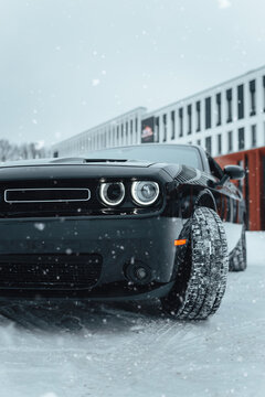 Vinnitsa; Ukraine; January 17, 2021: Black Dodge Challenger drives in the snow near an office shopping center.