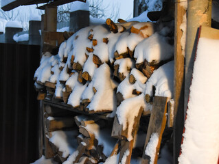 Firewood covered with snow close-up in the evening
