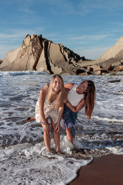 Friends laughing standing in ocean waves and flysch