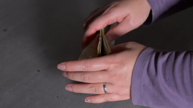 Close up woman's hands holding a small stack of $100 CAD Canadian bills